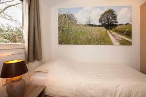 Hezingen的住宿－Bos en Heide，卧室配有一张床,墙上挂有绘画作品