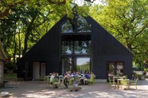 eine Gruppe von Menschen, die vor einem schwarzen Gebäude an Tischen sitzen in der Unterkunft Bos en Heide in Hezingen