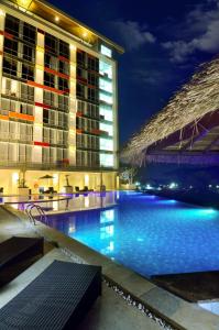 a swimming pool in front of a building at night at Ascent Premiere Hotel and Convention in Malang