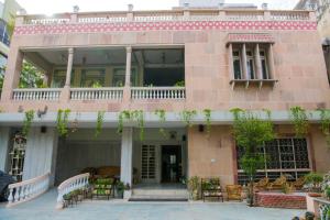 um edifício cor-de-rosa com uma varanda, mesas e cadeiras em Tara Niwas em Jaipur