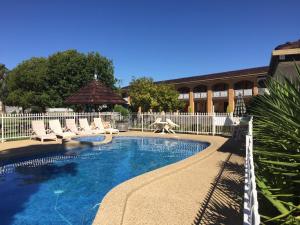 a swimming pool with chairs and a white fence at Lakeview Motel in Yarrawonga