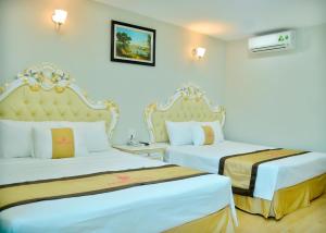 two beds in a hotel room with white walls at Phuong Hoang Hotel 2 in Sầm Sơn