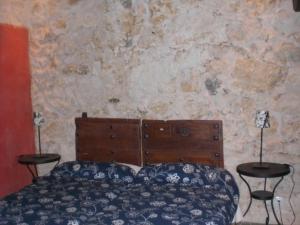 1 dormitorio con 1 cama con 2 mesas y pared de piedra en Casa Rural CASILLAS DEL MOLINO-Segovia, en Carbonero de Ahusín