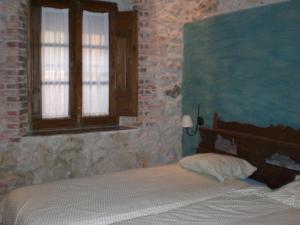 1 dormitorio con cama y pared de ladrillo en Casa Rural CASILLAS DEL MOLINO-Segovia, en Carbonero de Ahusín