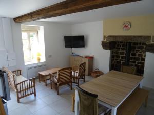 LA COURTEILLE في Saint-Fraimbault-sur-Pisse: غرفة معيشة مع طاولة وكراسي ومدفأة