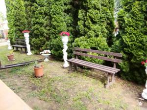 dos bancos de parque con flores en un jardín en Rubin Apartman, en Hajdúszoboszló