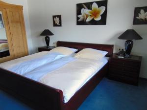 1 cama en un dormitorio con 2 lámparas y una flor en la pared en Landhaus Kogel, en Ofterschwang