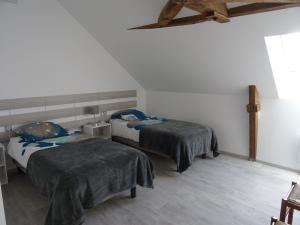 LA COURTEILLE في Saint-Fraimbault-sur-Pisse: غرفة نوم بسريرين وارضية خشبية