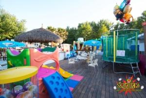un parco giochi con scivolo, sedie e ombrelloni di Hotel Loretta a Rimini
