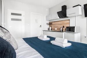 a white room with a bed with towels on it at Unique Apartments - Browar Gdański in Gdańsk
