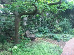 un banco de parque bajo un árbol junto a un camino de ladrillo en Eden Lodge Paris, en París