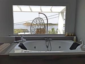 una grande vasca da bagno bianca in una stanza con finestra di Hyperion Hotel a Myrties