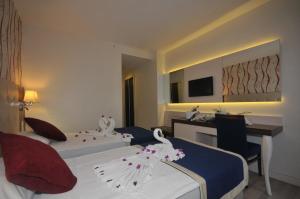 Una habitación de hotel con dos camas con cisnes. en Kleopatra Micador Otel en Alanya