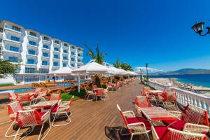 a row of chairs and tables on a deck next to the ocean at Hotel Saranda Palace in Sarandë