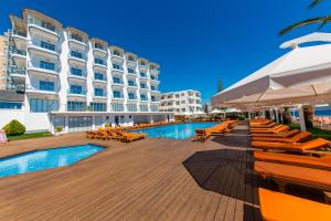 a resort with a pool and chairs and a building at Hotel Saranda Palace in Sarandë