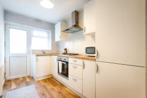 a kitchen with white cabinets and a refrigerator at Generous House near The Liberty Stadium in Swansea