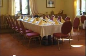 einen langen Tisch mit Stühlen und einem weißen Tischtuch in der Unterkunft Hotel am Kurpark in Schönebeck
