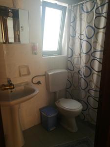 a bathroom with a toilet and a sink and a window at Adamas Rooms in Palaiochora