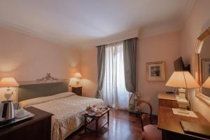 a hotel room with a bed, table, chairs and a lamp at Relais Ducale in Gubbio