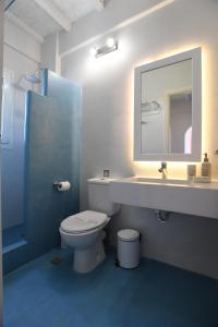 a bathroom with a toilet and a sink and a mirror at Nostos Beachfront Apartments & Studios in Agios Ioannis