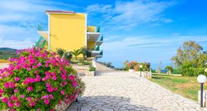a building with pink flowers in front of a sidewalk at Summer Sun in Skala