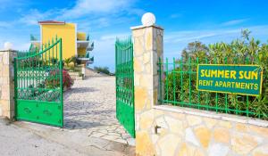 a green gate with a sign that reads summer sun and fresh apartments at Summer Sun in Skala