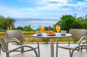 a table with a plate of food and two glasses of orange juice at Summer Sun in Skala