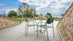 a patio with a table and chairs on a stone wall at Summer Sun in Skala