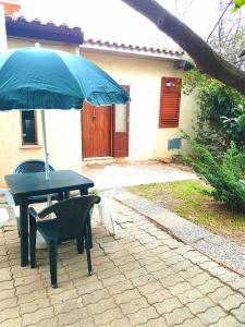 - une table et des chaises avec un parasol sur la terrasse dans l'établissement villini TotoeNita n 1 loc Capo Bianco di Capo Rizzuto, à Capo Rizzuto