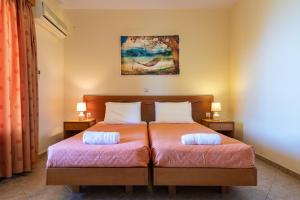 a bedroom with two beds and a painting on the wall at Summer Sun in Skala