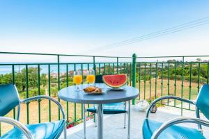 a table with a bowl of fruit and two glasses of orange juice at Summer Sun in Skala