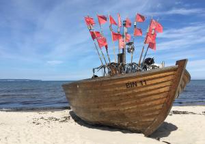 a wooden boat on the beach with flags on it at Hotel Pension Haus Colmsee in Binz