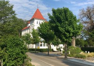 un grand bâtiment blanc avec un toit rouge dans l'établissement Hotel Pension Haus Colmsee, à Binz