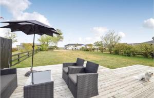 a patio with two chairs and an umbrella and a dog at Three-Bedroom Holiday Home In Juelsminde in Sønderby