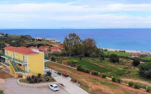 a yellow house with a car parked next to the ocean at Summer Sun in Skala