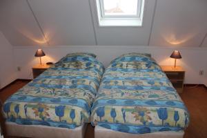 two beds in a small room with two lamps at Finistère in Oosterend