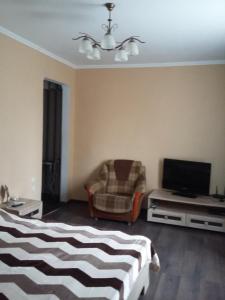 1 dormitorio con 1 cama, 1 silla y TV en Агрба 19/1 Квартира, en Pitsunda