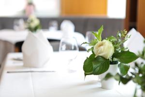 a white vase filled with flowers sitting on a table at Hotel Hauser Boutique in Nuremberg