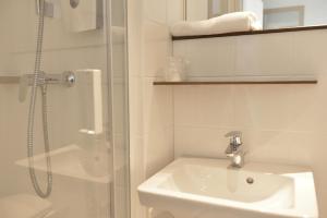 een witte badkamer met een wastafel en een douche bij Premiere Classe Reims Nord - Bétheny in Bétheny