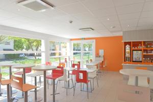 a restaurant with tables and chairs and windows at Premiere Classe Reims Nord - Bétheny in Bétheny