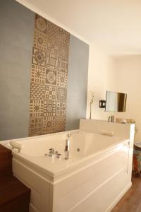 a bathroom with a white tub with a tile wall at Unique luxury apartment and rooms in Rome