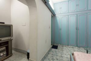 Zimmer mit einem TV und einer Wand mit blauen Schränken in der Unterkunft Sangleela in Neu-Delhi