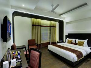 ein Schlafzimmer mit einem großen Bett und einem Schreibtisch mit einem Tisch in der Unterkunft Hotel Godwin Deluxe -Near New Delhi Railway Station - Paharganj in Neu-Delhi