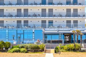 een gebouw met blauwe balkons op het strand bij Hotel Delle Nazioni in Caorle