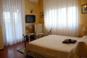 a bedroom with a bed and a chair and a television at Apartment Terrazza Greca in Agrigento
