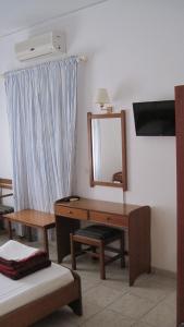 マスーリーにあるタティーズ アパートメンツのデスク、鏡、ベッドが備わる客室です。