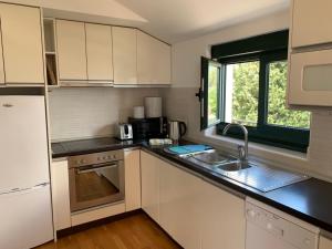 - une cuisine avec des placards blancs et un évier dans l'établissement Monteview Loft Apartment, à Herceg-Novi