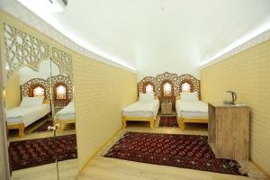 a room with two beds and a table and a rug at Muso To'ra Hotel- boutique in Khiva