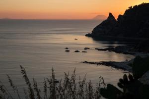 a sunset over the ocean with rocks in the water at Hotel Santa Chiara in Capo Vaticano