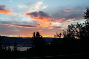 a sunset over a body of water with trees at Björkin – Cozy Cabin with excellent view in Akureyri